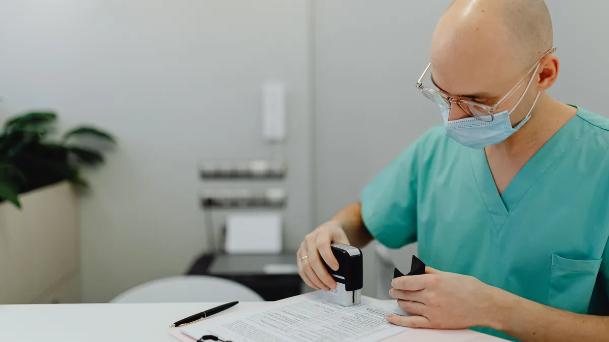 Medical professional in scrubs reviewing documents at an office desk.