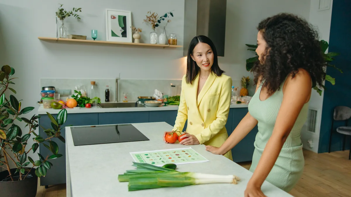 Two women discussing a healthy diet in a modern kitchen with fresh vegetables.