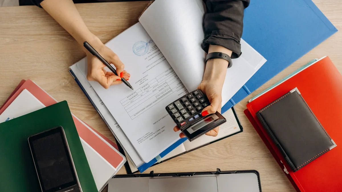 Accountant analyzing financial documents with a calculator on a desk, highlighting business tasks.
