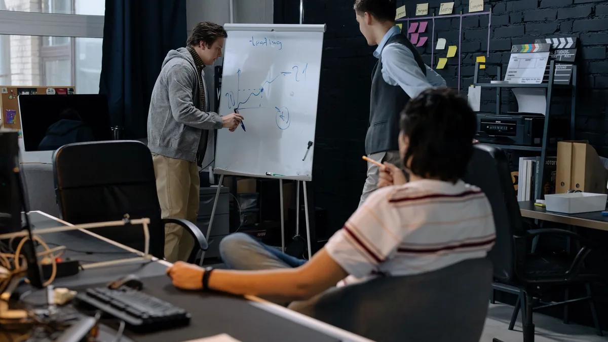 Business team in a modern office brainstorming ideas on a whiteboard. Engaged discussion and planning.
