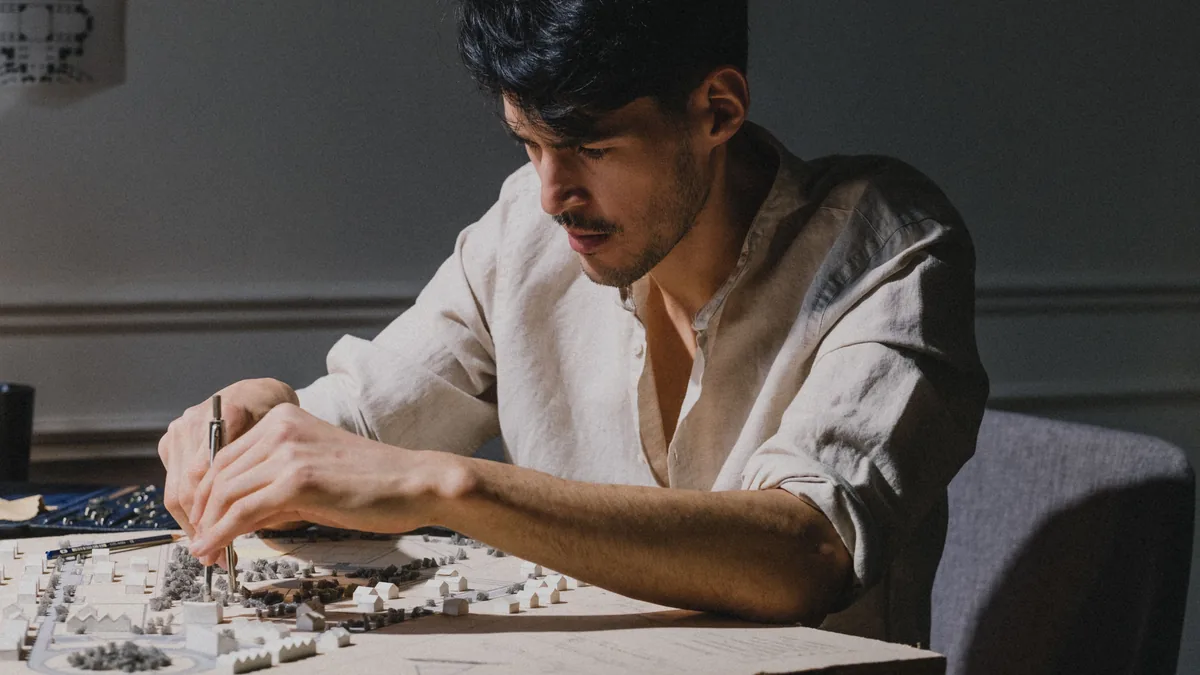 Architect focused on designing a detailed architectural model indoors under soft lighting.