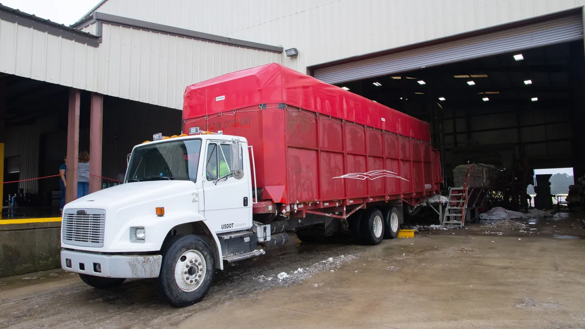 Red trailer truck at a warehouse loading dock, ready for delivery.