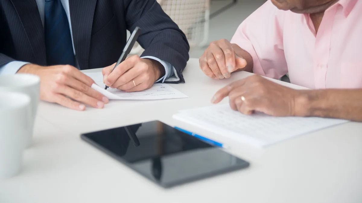 Two professionals discussing and signing documents in a business meeting.