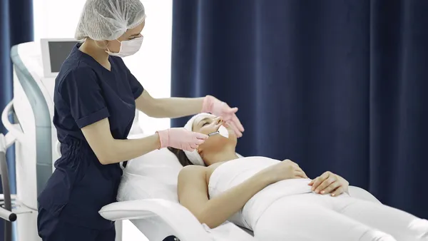 Esteticista realizando tratamento facial em cliente na clínica