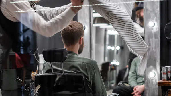 Barbeiro cortando o cabelo de um cliente na cadeira da barbearia