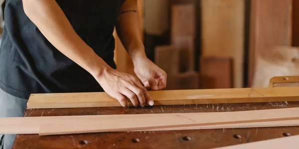 Artesão trabalhando com tábuas de madeira em uma marcenaria