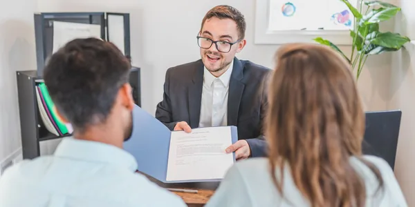 Consultor apresentando um contrato a clientes em um escritório moderno