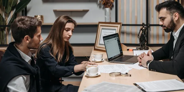 Três profissionais analisando documentos durante uma reunião com café