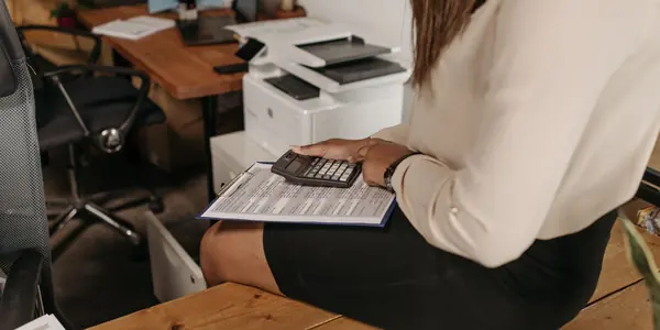 Prestadora de serviço conferindo documentos com calculadora no escritório, representando a emissão da NFS-e pelo Emissor Nacional