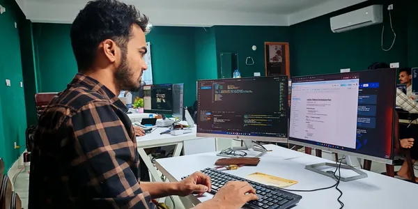 Desenvolvedor trabalhando em dois monitores com c&oacute;digo aberto em escrit&oacute;rio