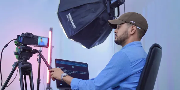 Criador de conte&uacute;do gravando em est&uacute;dio com c&acirc;mera em trip&eacute;, softbox e notebook