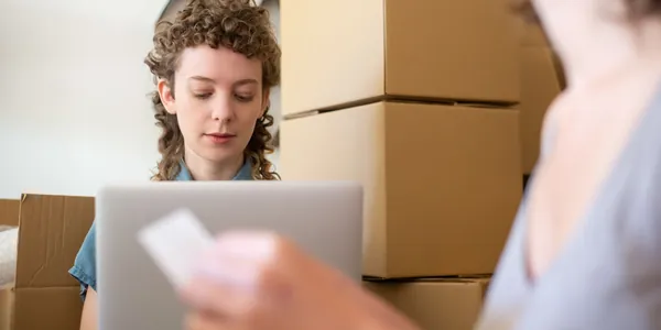 Mesa de trabalho de loja virtual com caixas prontas para envio, notebook aberto e blocos de anota&ccedil;&atilde;o