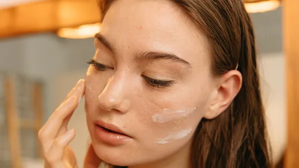 Aplicação de creme no rosto em atendimento de estética