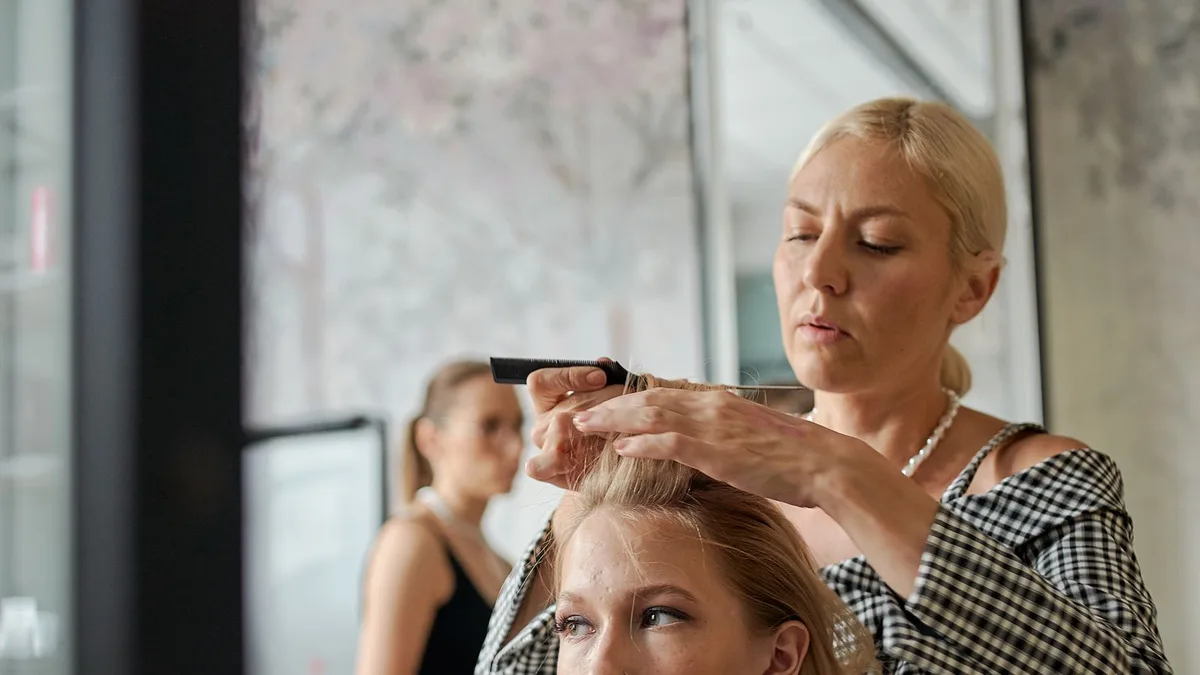 Cabeleireira alisando o cabelo de uma cliente