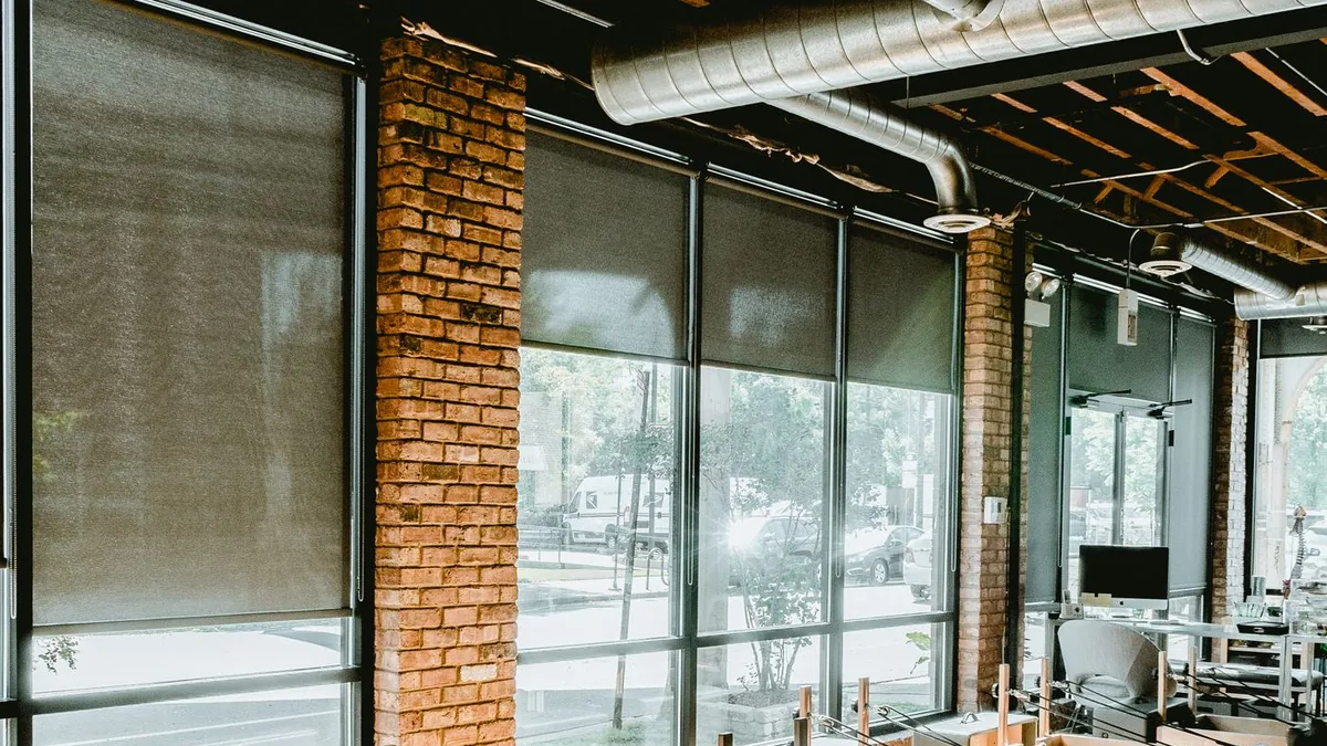 Interior de um est&uacute;dio de pilates com aparelhos e janelas amplas