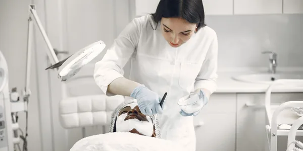 Mulher recebendo tratamento facial na maca de uma clínica de estética
