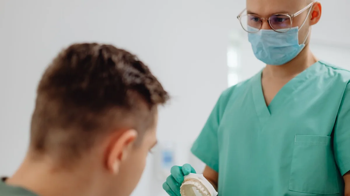 Dentista mostrando um modelo dental ao paciente durante a consulta