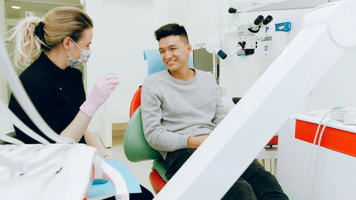 Dentista atendendo um paciente sorridente na cadeira do consultório