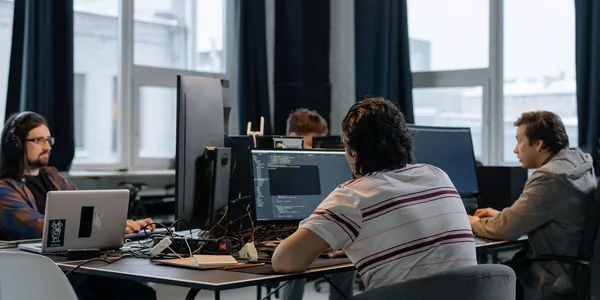 Equipe de desenvolvedores trabalhando junto em computadores no escritório