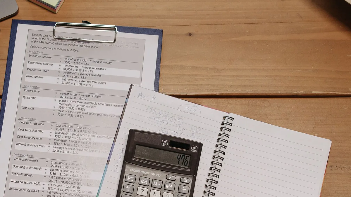 Calculadora, prancheta e anotações sobre a mesa de trabalho