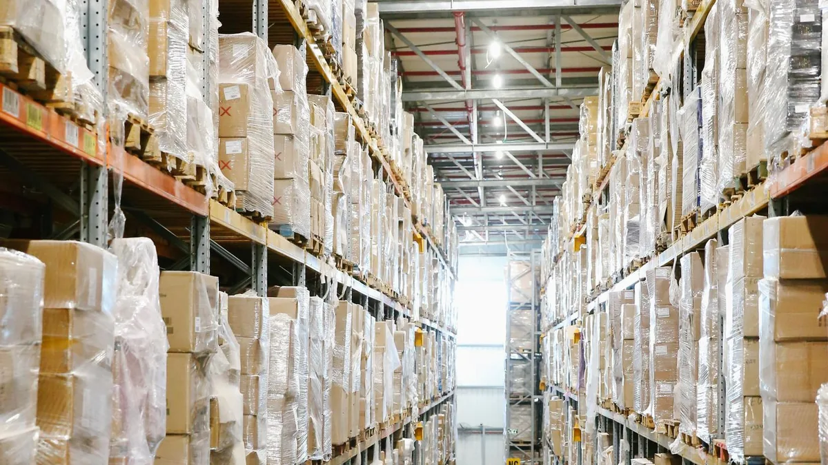 Corredor de um galp&atilde;o com mercadorias embaladas nas prateleiras