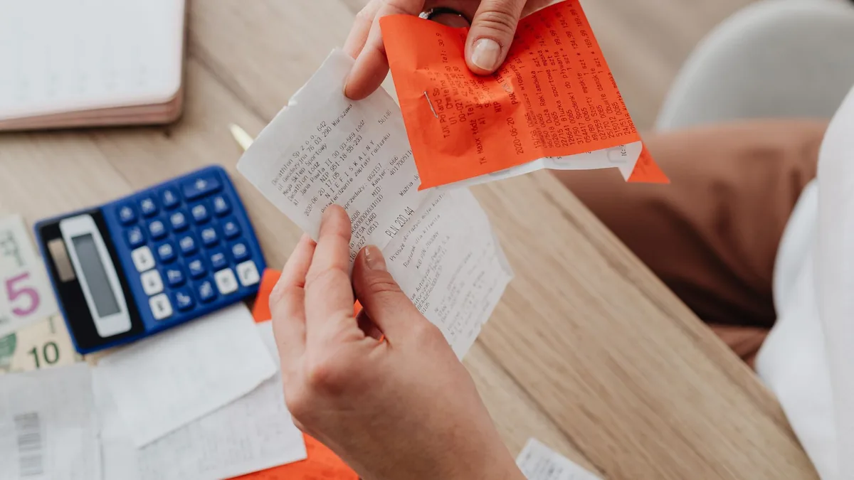 Vista de cima de uma mesa com calculadora, recibos e anotações de contas