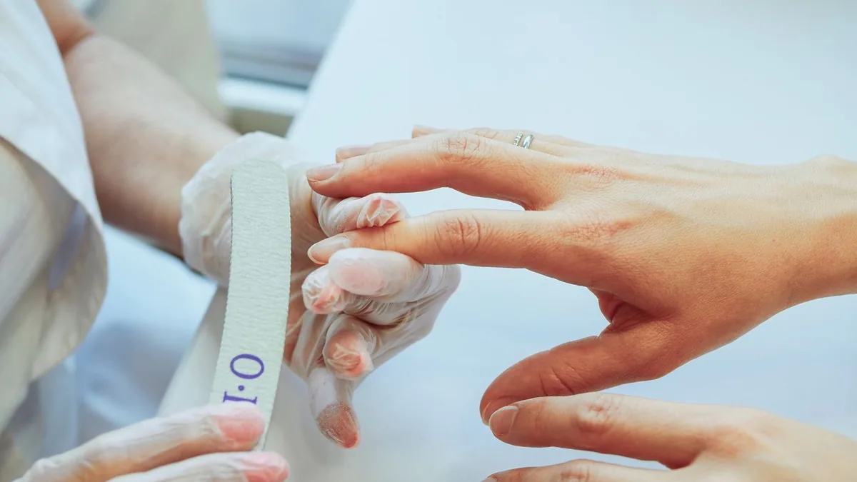Manicure lixando as unhas de uma cliente no salão