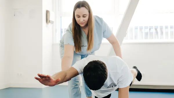 Fisioterapeuta conduzindo exercício com paciente na sala de atendimento