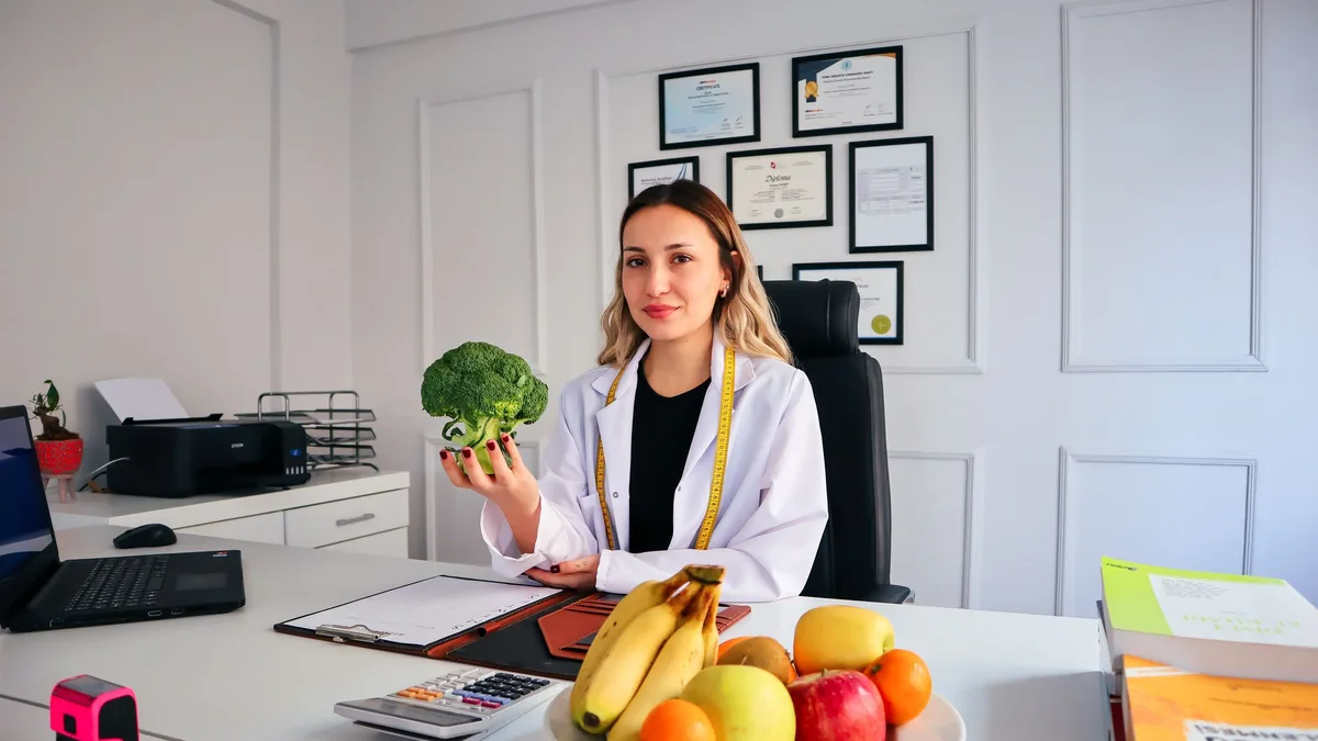 Nutricionista no consultório com frutas e legumes sobre a mesa