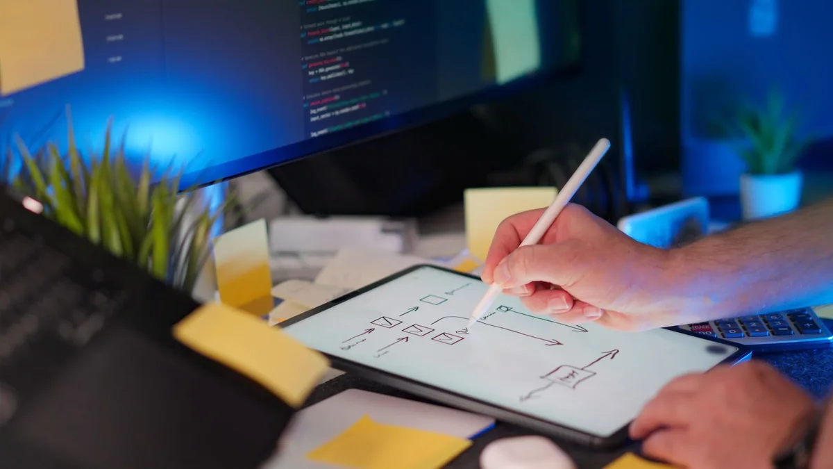Mão desenhando o esboço de uma tela de aplicativo em um tablet.