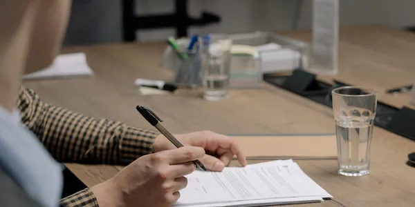 Pessoa fazendo contas com calculadora, papéis e documentos sobre a mesa, calculando quanto custa abrir empresa