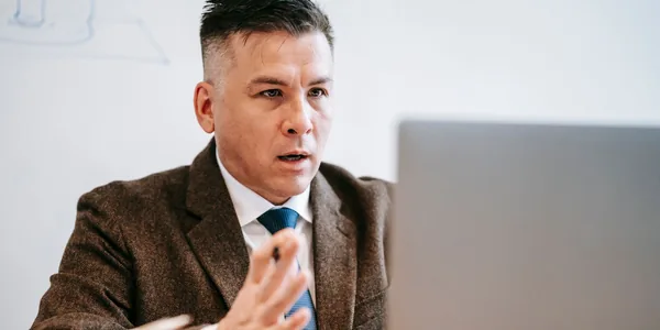Empresário de terno participando de uma reunião online pelo notebook