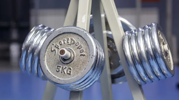 Instrutor orientando um aluno no aparelho de musculação da academia