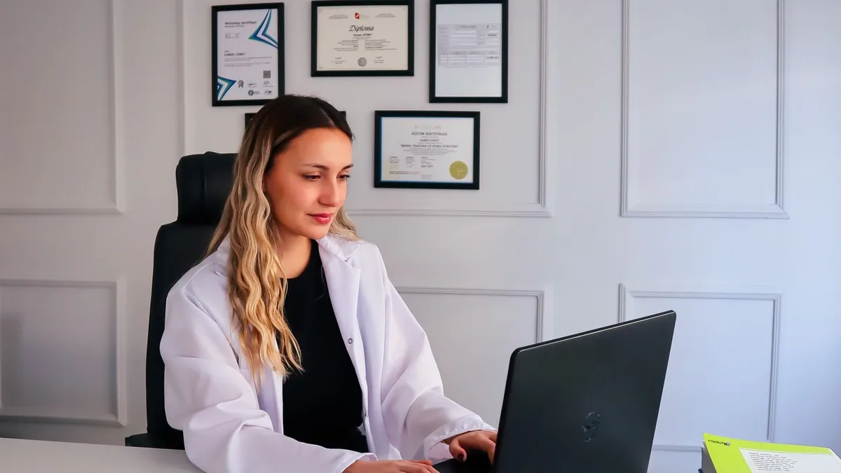 Nutricionista no consultório, com frutas sobre a mesa e o computador aberto