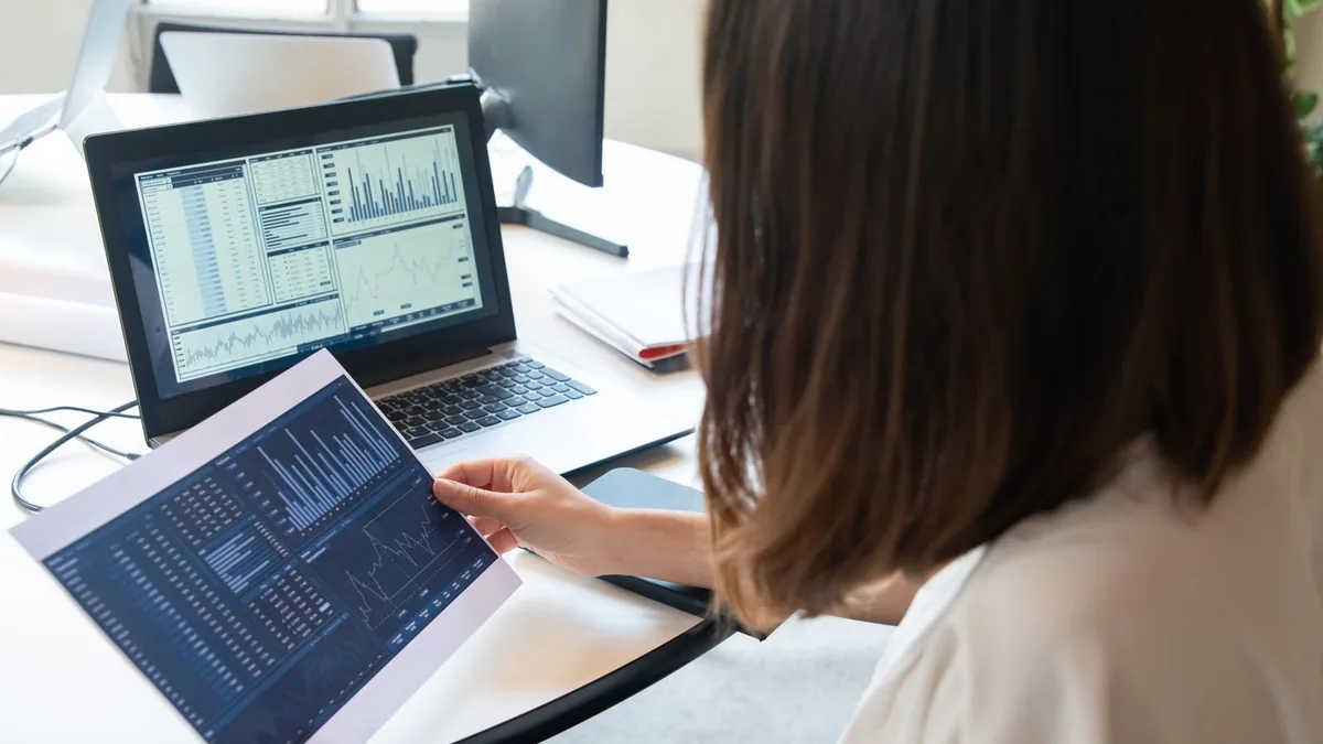 Empreendedora digital analisando o relatório de vendas da plataforma no notebook