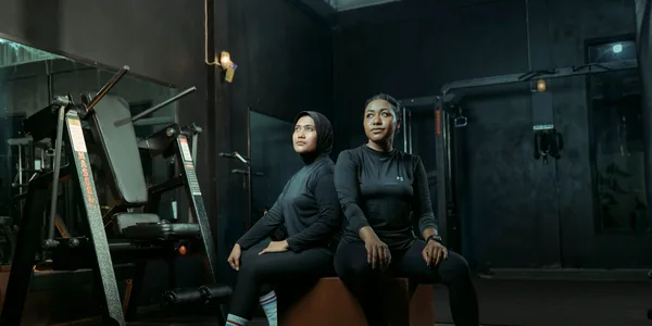 Duas alunas de roupa de treino sentadas no salão da academia