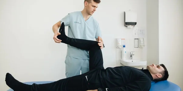 Fisioterapeuta acompanhando o alongamento da perna de uma paciente na maca