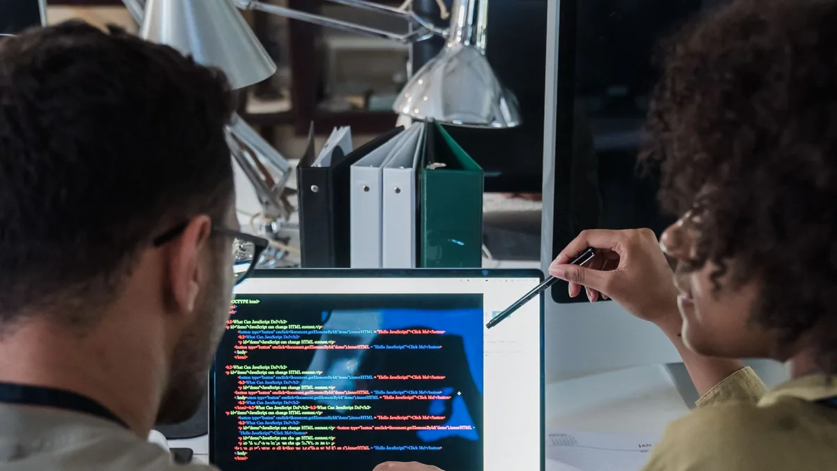 Dois desenvolvedores discutindo o código no notebook dentro do escritório