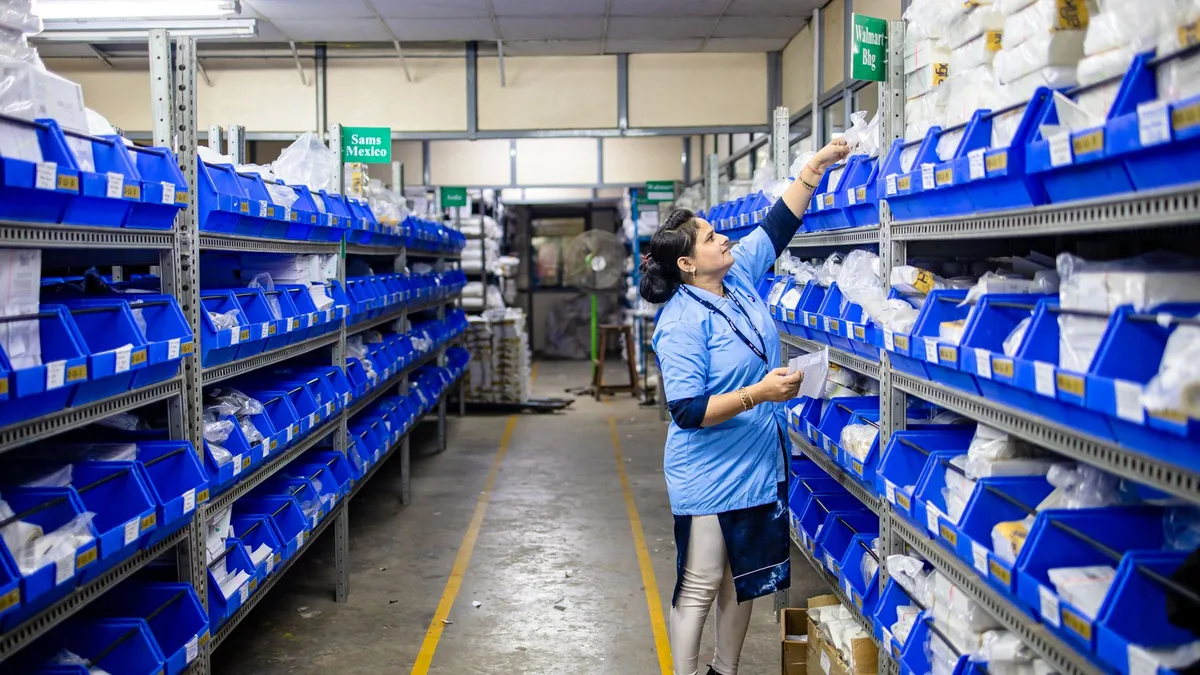 Funcionária organizando o estoque em um corredor de prateleiras do galpão