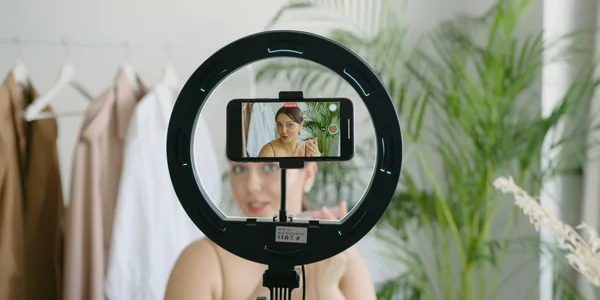 Criadora gravando um vídeo com o celular ao lado de uma luz de anel