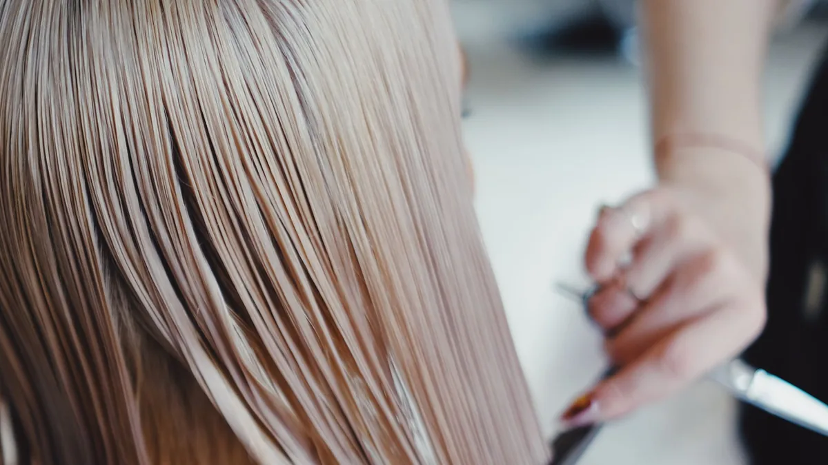 Mãos penteando um cabelo longo e liso na bancada do salão