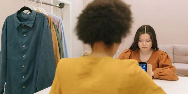 Duas profissionais trabalhando em um ateliê com arara de roupas ao fundo