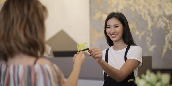 Florista sorrindo ao receber pagamento de cliente em loja, representando negócios que vendem para pessoa física na Reforma Tributária