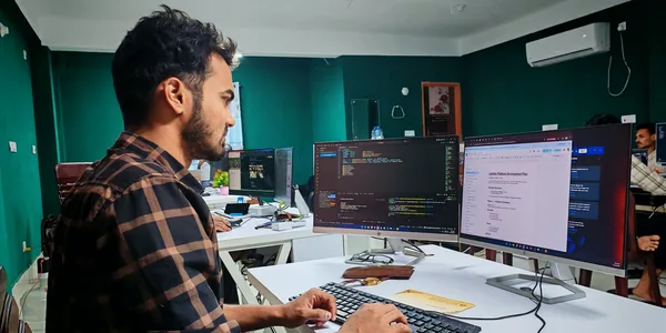 Desenvolvedor de software trabalhando em setup com dois monitores, ilustrando a Reforma Tributária para empresas de tecnologia