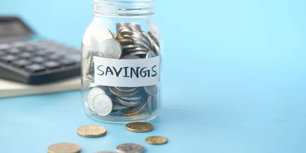 Pote de moedas ao lado de calculadora representando o capital de giro afetado pelo split payment