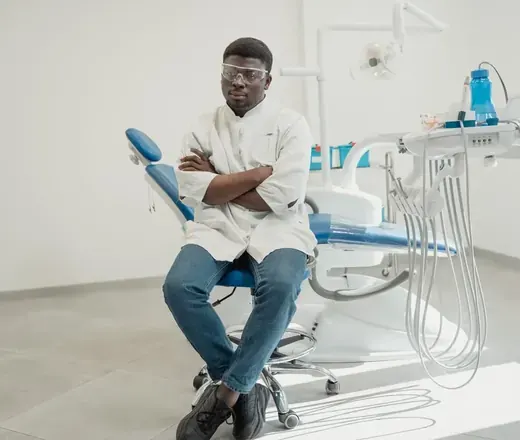 Dentista no consult&oacute;rio, ao lado da cadeira odontol&oacute;gica